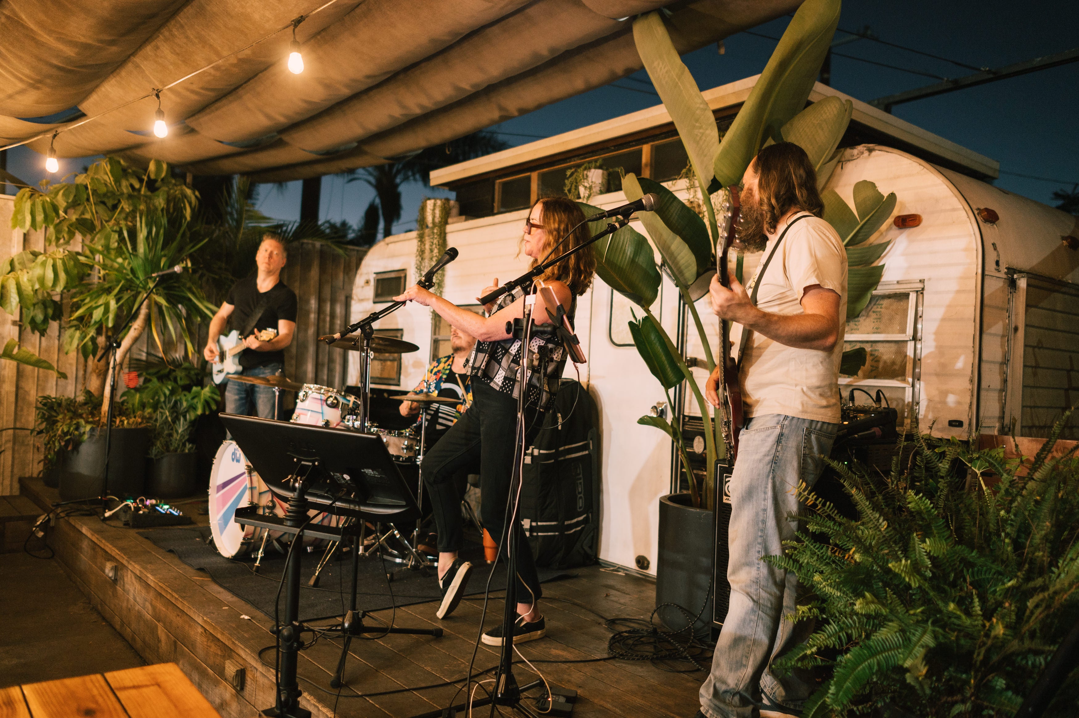 Three people performing at open mic night at Alana's in Mar Vista on the patio in early evening. 