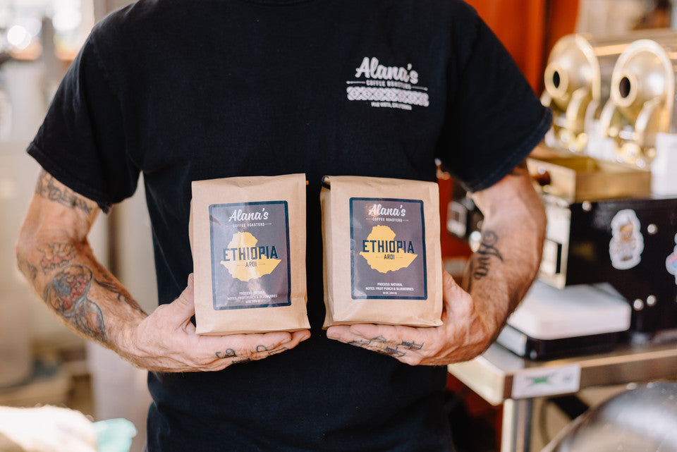 A man holds two bags of Ethiopian ardi coffee.